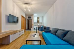 ein Wohnzimmer mit einem blauen Sofa und einem Tisch in der Unterkunft Vila Zlatibor luxury & spa in Zlatibor