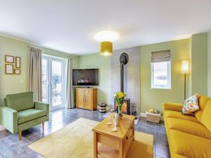 a living room with a yellow couch and a chair at Humbug House in Lower Soudley