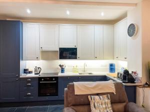 a kitchen with white cabinets and a couch in a room at The Boathouse in Appledore