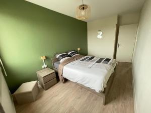 um quarto com uma cama e uma parede verde em Appartement vu mer em La Faute-sur-Mer