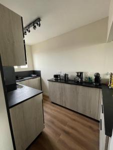 uma grande cozinha com bancadas pretas e pisos de madeira em Appartement vu mer em La Faute-sur-Mer