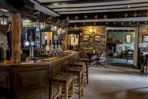 a bar in a pub with wooden stools at White Hart Inn in Bouth