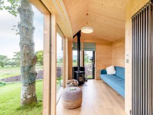 The Curve At Caerlaverock Estate في Glencaple: منزل خشبي مع أريكة زرقاء وشجرة