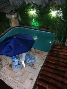 duas cadeiras e um guarda-sol junto a uma piscina em Beleza Tropical Pousada Hotel em Fortaleza