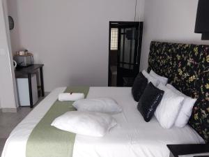 a white bed with pillows on it in a room at The Guesthouse Klerksdorp in Klerksdorp