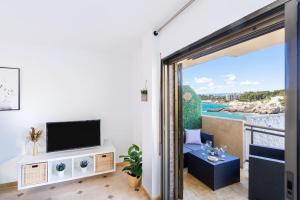 a living room with a television and a balcony at 1ºlineaMar-exclusive-BBQ-wifi-Relax-PortAventura6 in Salou