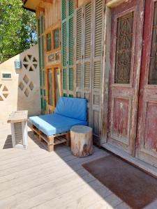 El Sheesh by Barefoot in Tunis في Ibshawāy: جلسة على كرسي ازرق بجانب باب