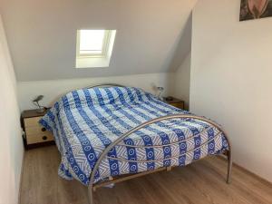 a bed with a blue and white comforter in a room at Het Zonnetje Zonnebeke in Zonnebeke