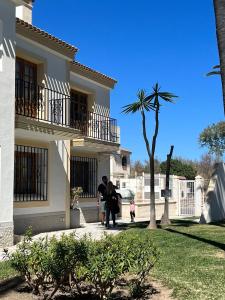 dos personas de pie fuera de una casa con una palmera en Apartamento 70 Vera Playa en Vera