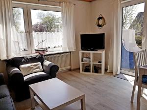 een woonkamer met een bank en een tv bij Birkenhof Neuharlingersiel in Neuharlingersiel