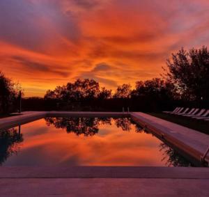 una puesta de sol sobre una piscina con un cielo nublado en Relais CastelBigozzi en Monteriggioni