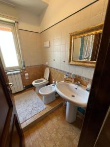 a bathroom with a sink and a toilet and a mirror at La casa nel villaggio dei pescatori in Spadafora
