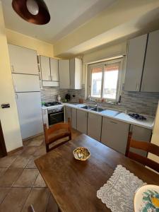 a kitchen with a wooden table and a kitchen with white appliances at La casa nel villaggio dei pescatori in Spadafora