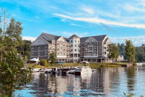 a large building on a lake with boats in the water at Saranac Waterfront Lodge in Saranac Lake