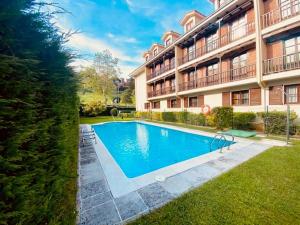 a swimming pool in front of a building at Apartamentos Club Condal in Comillas