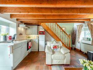 a kitchen with white cabinets and a wooden staircase at Ty Berllan - Oab in Gowerton