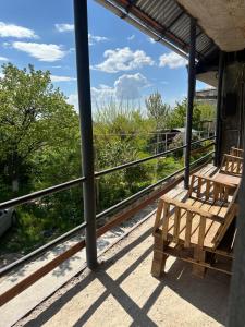 two benches sitting on a porch with a view of trees at Family Guest House in Yerevan