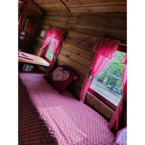 Schlafzimmer mit einem Bett mit rosa Bettwäsche und einem Fenster in der Unterkunft La roulotte rose rouge in Valgorge