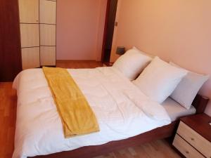 Una cama con sábanas blancas y una manta amarilla. en Rukadel - Poleska, en Wroclaw
