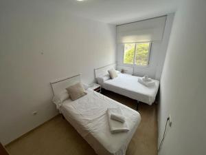 2 camas en una habitación pequeña con ventana en Apartamento a pie de playa con vistas al mar. en Sorvilán
