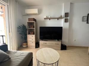 sala de estar con TV de pantalla plana y mesa en Apartamento a pie de playa con vistas al mar. en Sorvilán