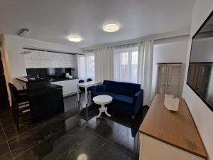 a living room with a blue couch and a kitchen at Apartament Helenka in Hajnówka