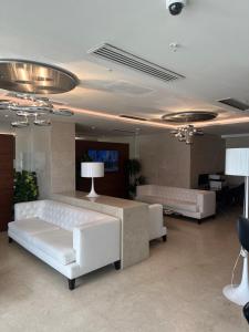 una sala de estar con 2 sofás blancos y una mesa. en Alliance Palace By Marriott, en Batumi