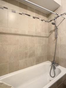 a white bath tub with a shower in a bathroom at Grand Appartement Paris et Disneyland 4pers in Neuilly-sur-Marne