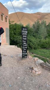 um sinal sentado na terra ao lado de um edifício em Dar Mezyana Dades em Aït Idaïr