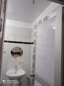 Baño blanco con lavabo y espejo en Casa Hospedaje VIRREY, en Jauja