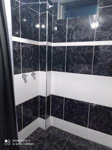 a bathroom with a shower with black and white tile at Casa Hospedaje VIRREY in Jauja