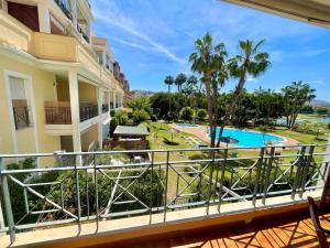d'un balcon avec vue sur la piscine et les palmiers. dans l'établissement Playa San Juan Golf, à Alicante