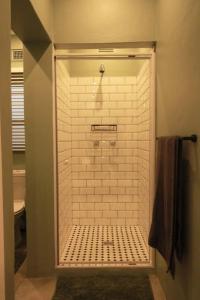 baño con ducha a ras de suelo con azulejos blancos en Clifton Home, en Richards Bay