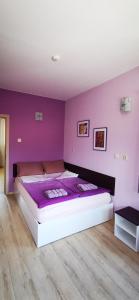 una camera da letto con un grande letto con pareti viola di Rose valley guest house a Kazanlŭk