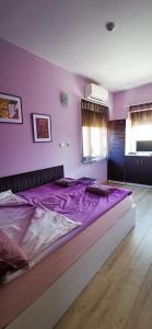 a large bed in a bedroom with purple walls at Rose valley guest house in Kazanlŭk