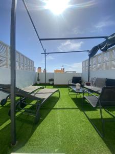 eine Dachterrasse mit Stühlen, einem Sonnenschirm und Gras in der Unterkunft CABO BEACH II in Cabo de Gata