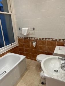 a bathroom with a tub and a toilet and a sink at Hadleigh Hotel in Eastbourne
