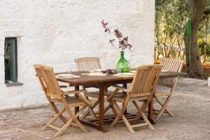 ein Holztisch mit vier Stühlen und eine Vase mit Blumen in der Unterkunft ITRIUM Homes & Suites in Valle d'Itria in Alberobello