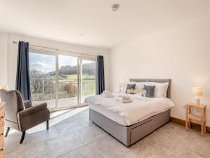 a bedroom with a bed and a chair and a window at Larchwood Lodge in Old Radnor