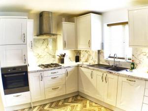 uma cozinha branca com armários brancos e um fogão em Pete's Place - 97a Grantley Gardens - Plymouth Devon em Plymouth