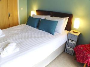 um quarto com uma grande cama branca com almofadas azuis em Pete's Place - 97a Grantley Gardens - Plymouth Devon em Plymouth