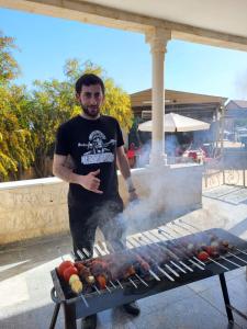 a man standing next to a barbecue grill at Madaba Camp Resort in Madaba