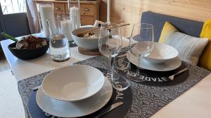 een tafel met borden en wijnglazen erop bij Le 41 du Lyret - Appartement type studio pour deux avec vue sur les Aiguilles dans Chamonix Centre in Chamonix-Mont-Blanc