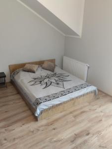 a bed in a white room with a wooden floor at Przytulny apartament w sercu Karkonoszy in Jelenia Góra