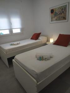 Habitación blanca con 2 camas y 2 ventanas en CHALET ARRILUCE Plaza de parking gratis en la playa SOLO FAMILIAS en Chiclana de la Frontera
