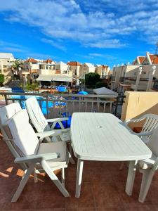 une table et des chaises blanches sur une terrasse avec piscine dans l'établissement Light and cosy apartment in 100 meters from the beach Costa Adeje, à Adeje