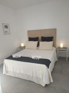 1 dormitorio con 1 cama blanca grande y 2 mesas en CHALET ARRILUCE Plaza de parking gratis en la playa SOLO FAMILIAS en Chiclana de la Frontera