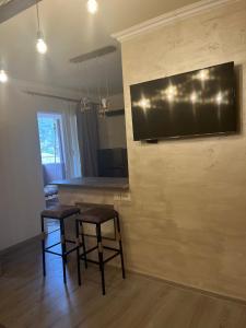 Sala de estar con 2 taburetes y TV en la pared en Милый Дом en Vanadzor