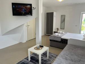 MB Apartments في أولتسينج: غرفة معيشة مع سرير وتلفزيون على جدار