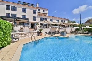 a large swimming pool in front of a building at Hotel & Restaurant Perla Riviera in Villeneuve-Loubet